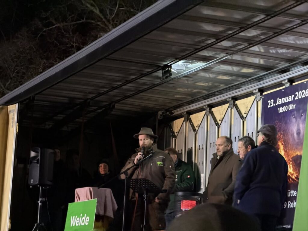 Mahnfeuer gegen Wolfsrisse in Rehe im Westerwald: Landwirte und Bürger versammeln sich auf einer Bühne, Redner spricht vor Publikum, Protest für den Schutz von Weidetieren und Bauern.